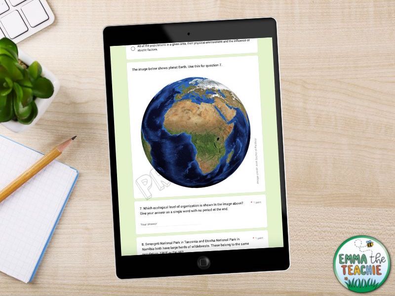 An iPad on a wooden desk showing a screenshot of a portion of a Google Form Quiz about ecology. The screenshot shows a picture of the earth and a short answer question.