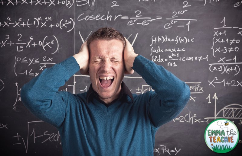 n image of a male teacher looking visibly stressed in front of a chalkboard. His hands are on the sides of his head, his eyes are squeezed shut, and his mouth is open as if screaming.