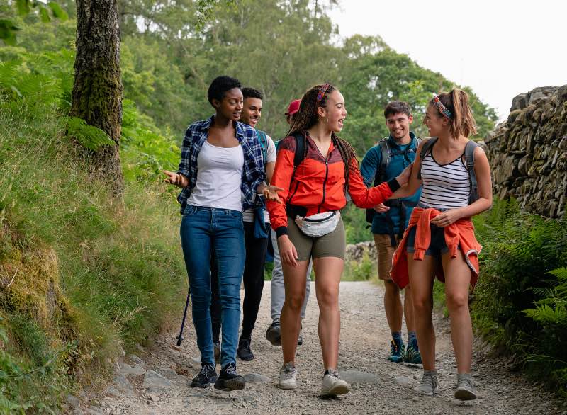 An image showing high school students on a field trip outside looking at nature on a hike.