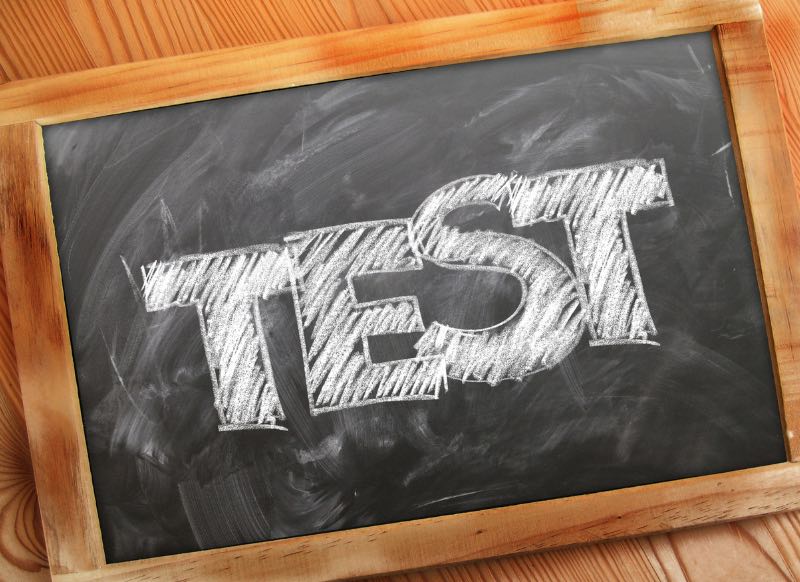 A chalkboard with the word “TEST” written on it with white chalk.