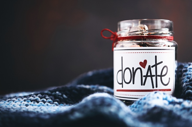 A jar resting on a blanket. The word “donate” is on the jar.