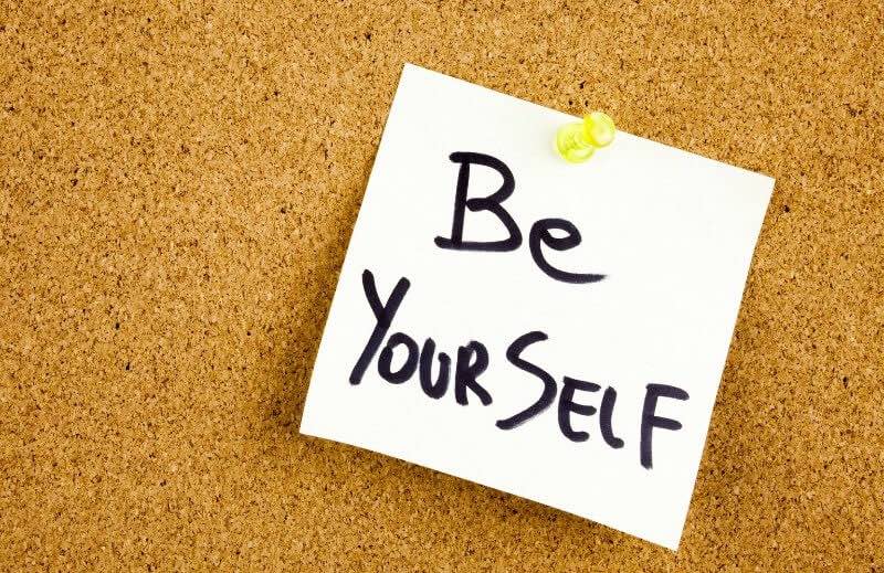 An image of a corkboard with a post-it note on it. The post-it reads, “Be Yourself.”