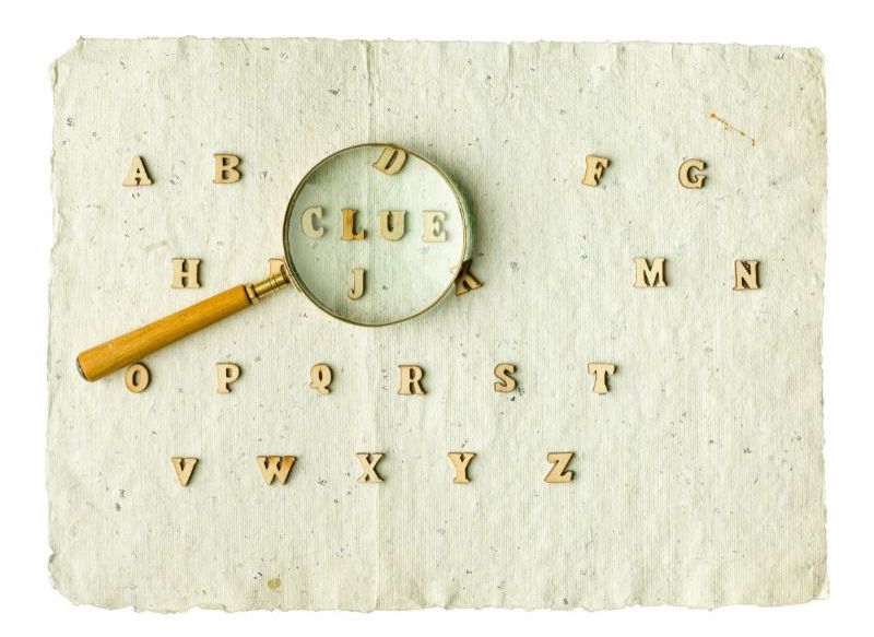 An image with a piece of paper and letters. A magnifying class is hovering over an area where the letters spell out, “Clue.”